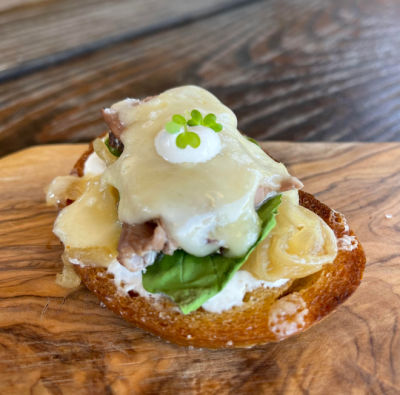 Melted Monterey Jack Cheese tops this roast beef crostini and caramelized onions, garnished with microgreens