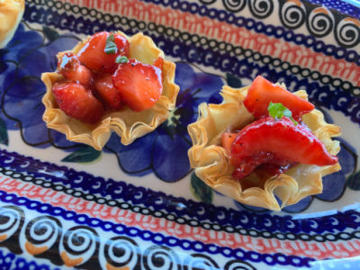 Fresh diced ripe strawberries in phyllo cups with melted brie and garnished with fresh torn basil